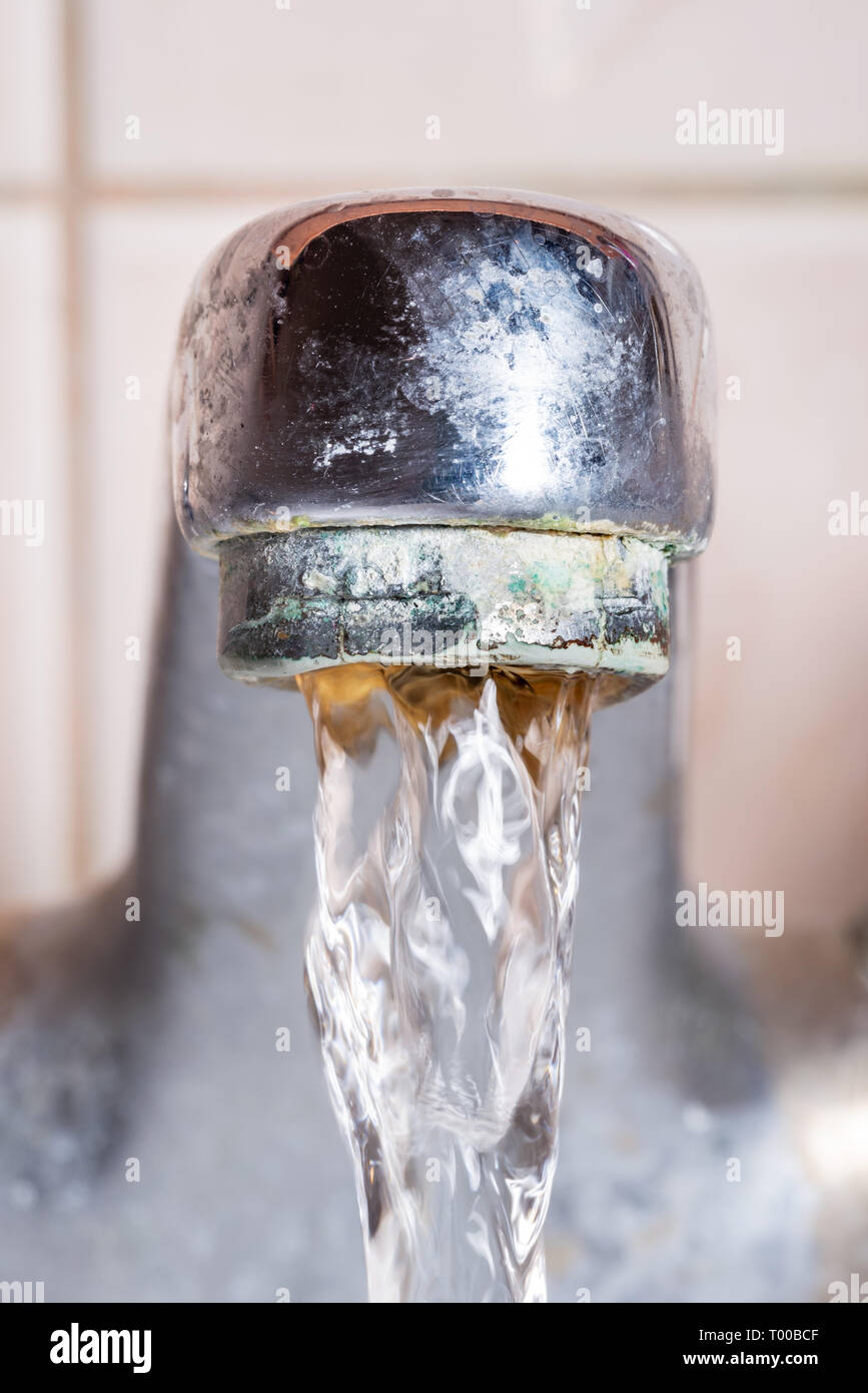 Vertical macro photo of a tap with water flowing strongly under high pressure Stock Photo