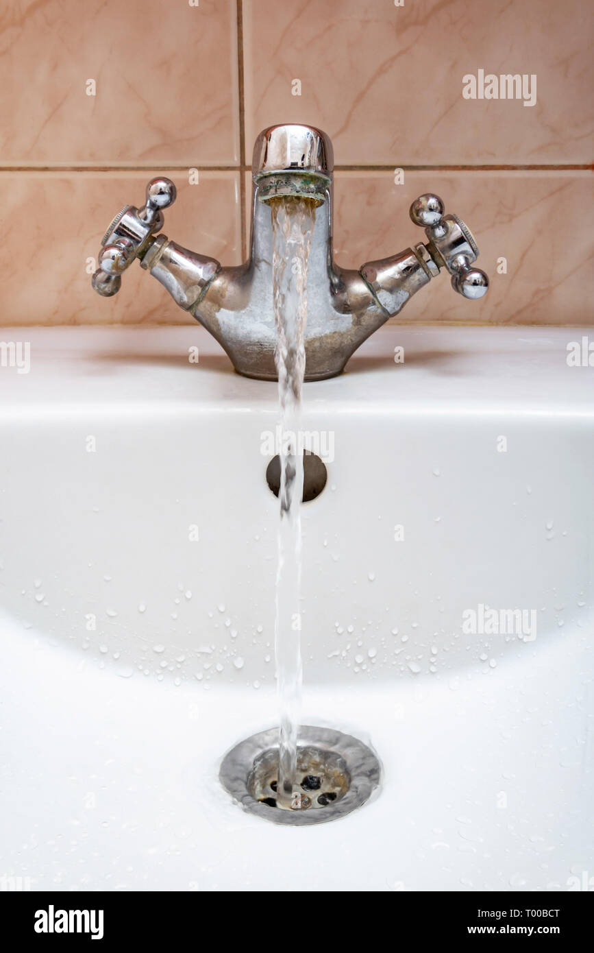 Vertical image of a tap with water flowing strongly under high pressure Stock Photo