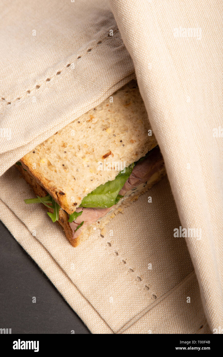 whole grain bread sandwich of steak, Stilton and spinach. delicious lunch time meal. organic with no single use wrapping, on a slate grey surface. Stock Photo