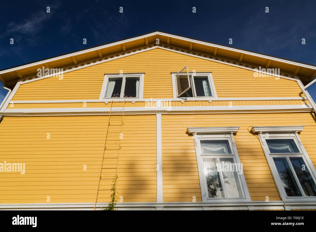 White windows on exterior side wall of a yellow two story house, Porvoo