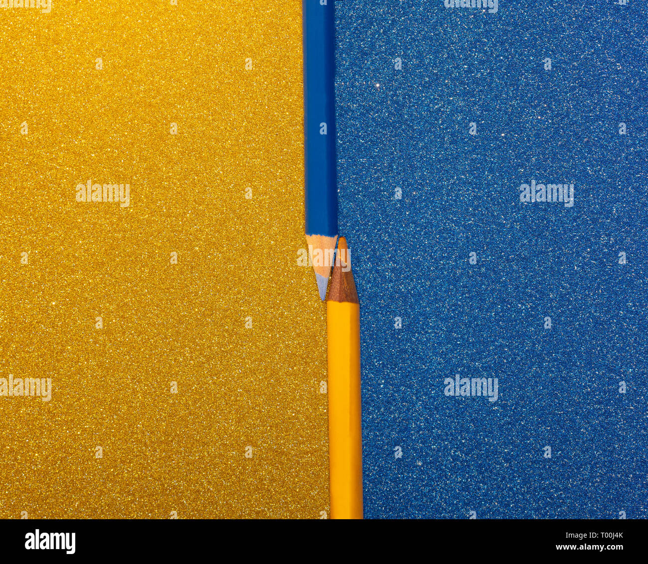 two pencils, blue and yellow on colored and brilliant cards placed contrasting the background, free space for text on both sides Stock Photo