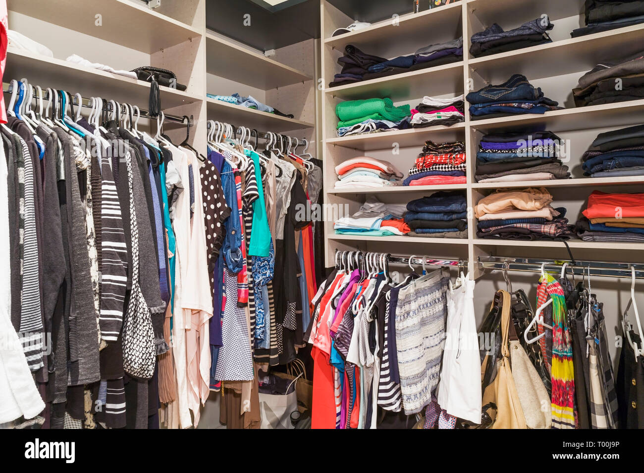 Walk-in closet with women's clothes on hangers and on shelves next to  master bedroom inside a luxurious contemporary bungalow style home Stock  Photo - Alamy