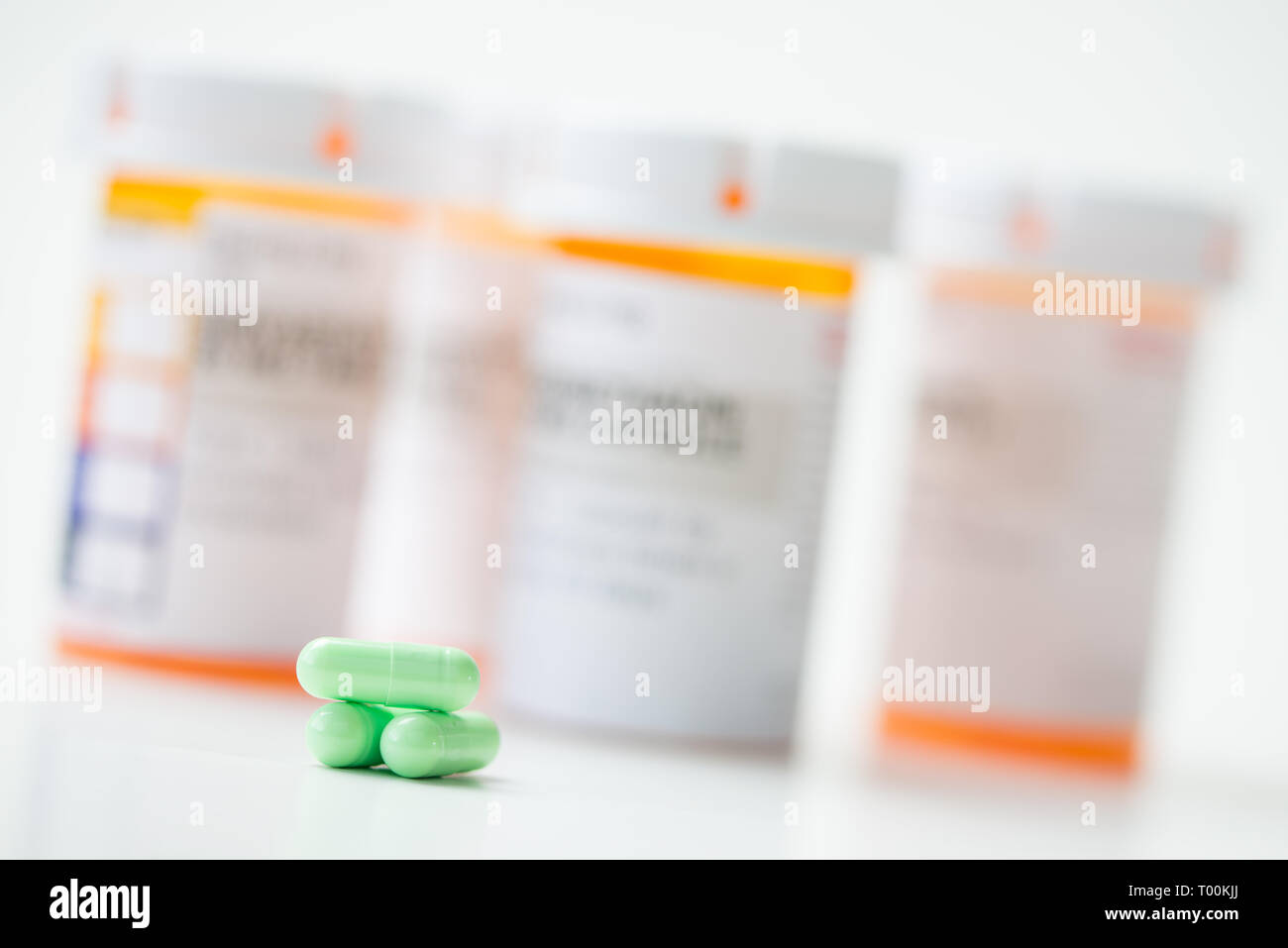 Green capsules in front of orange pharmacy bottles Stock Photo Alamy