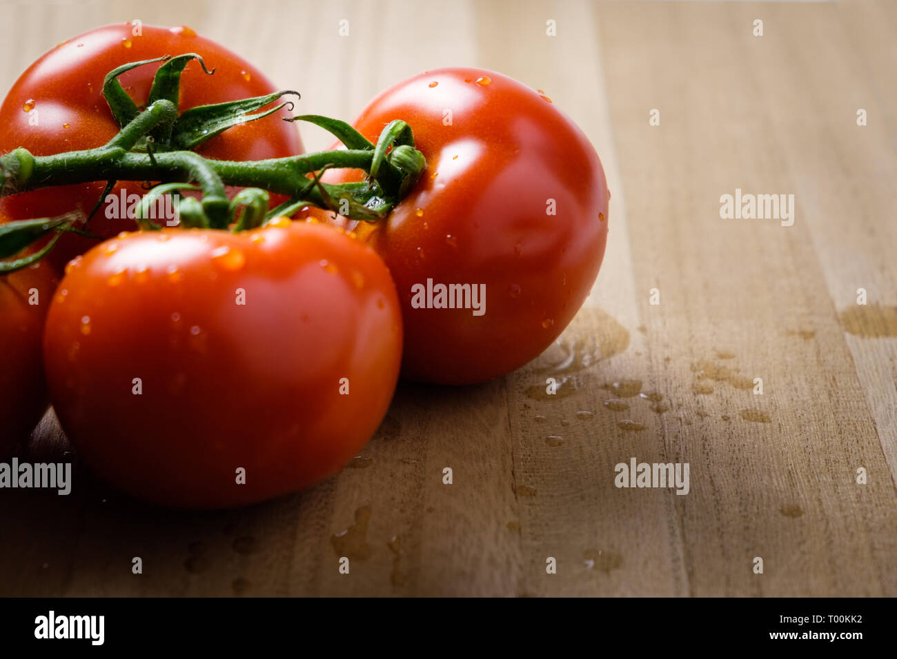 Tomatoes panicles on a wooden chopping board Stock Photo - Alamy