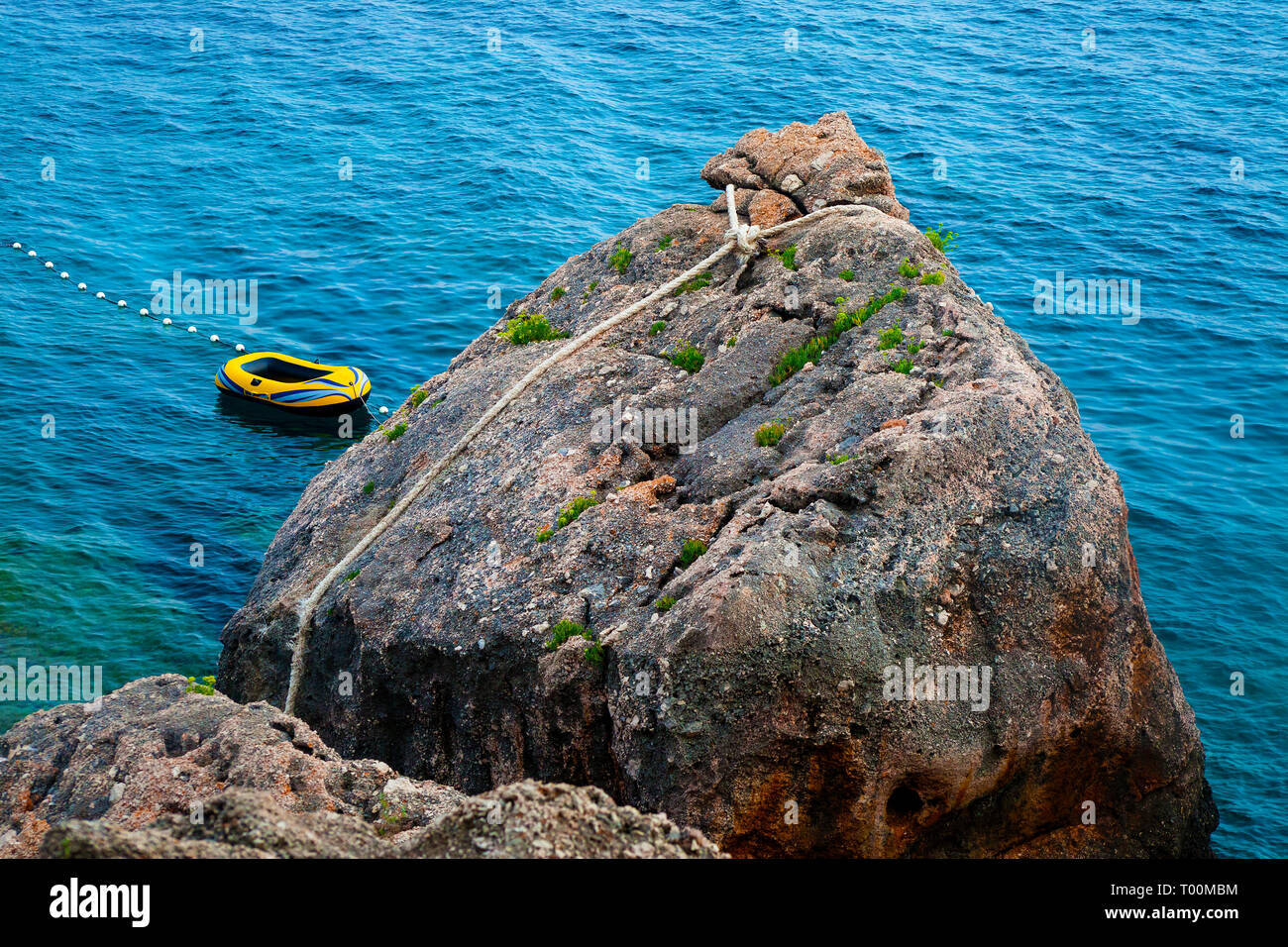 Inflatable yellow boat tied to a rock at beautiful seaside Stock Photo ...