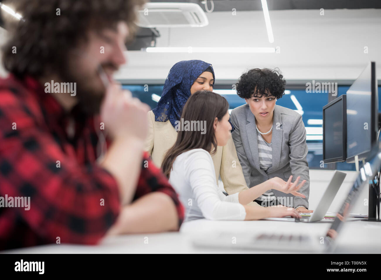 young multiethnics business team of software developers working together using laptop and desktop computer while writing programming code at modern st Stock Photo