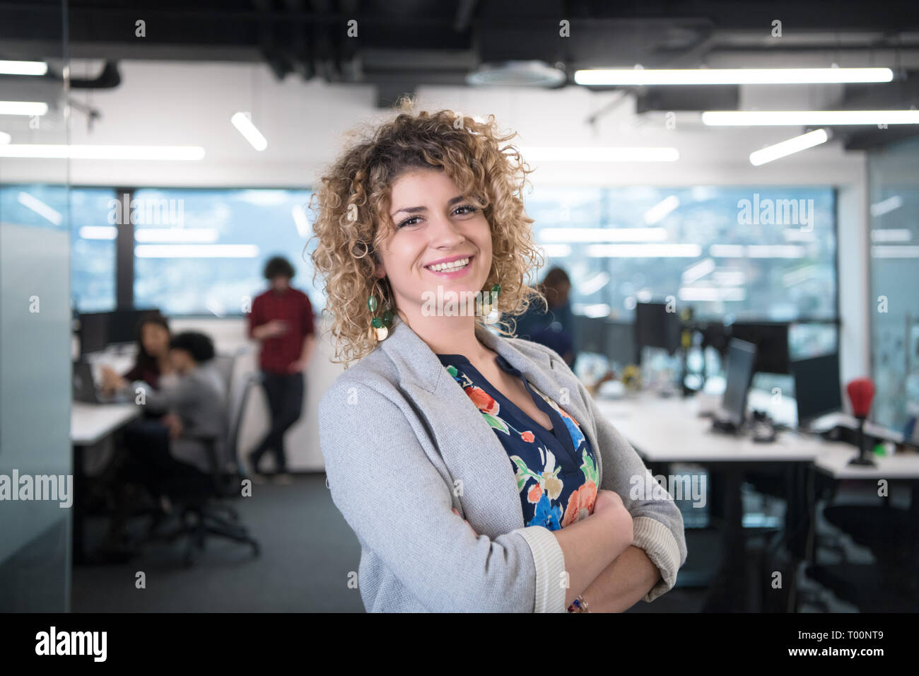 portrait of young female software developer at busy startup office with ...