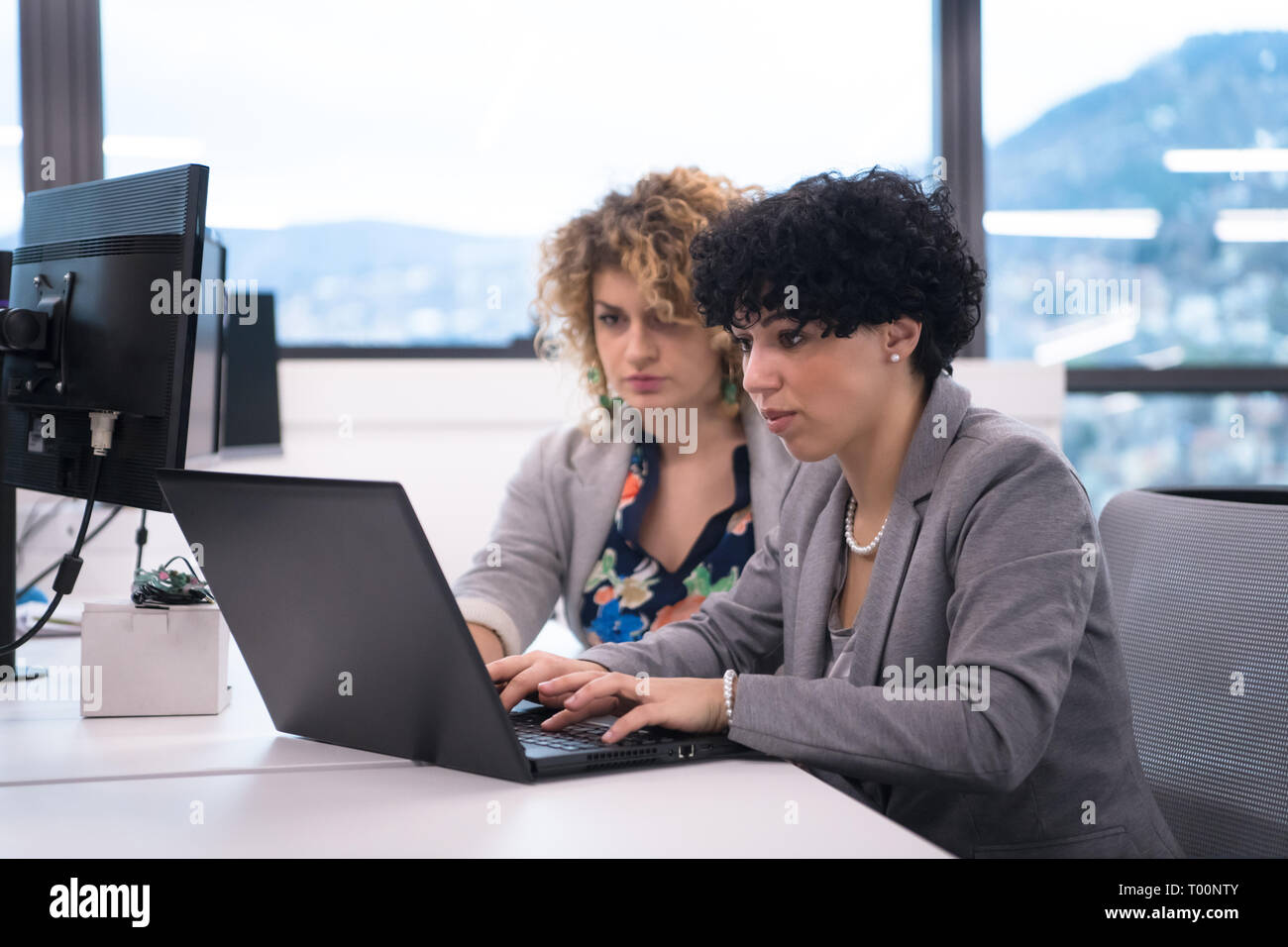 group of young female software developers using laptop computer while writing programming code at modern creative startup office Stock Photo