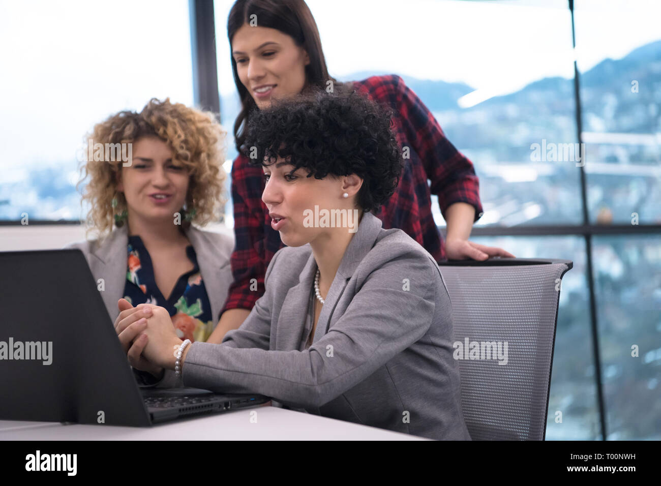 group of young female software developers using laptop computer while writing programming code at modern creative startup office Stock Photo