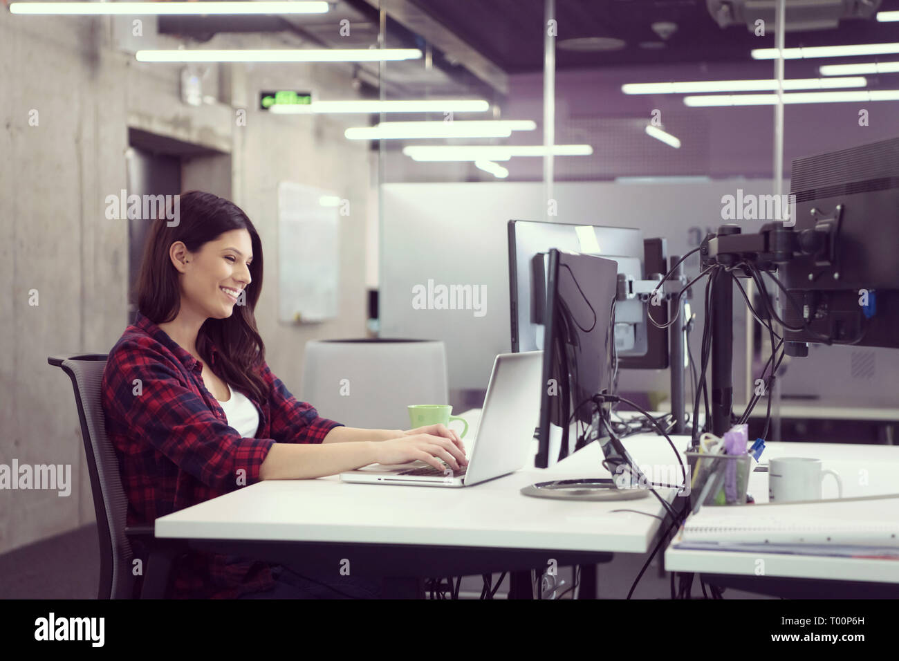 young female software developer using laptop computer while writing programming code at modern creative startup office Stock Photo