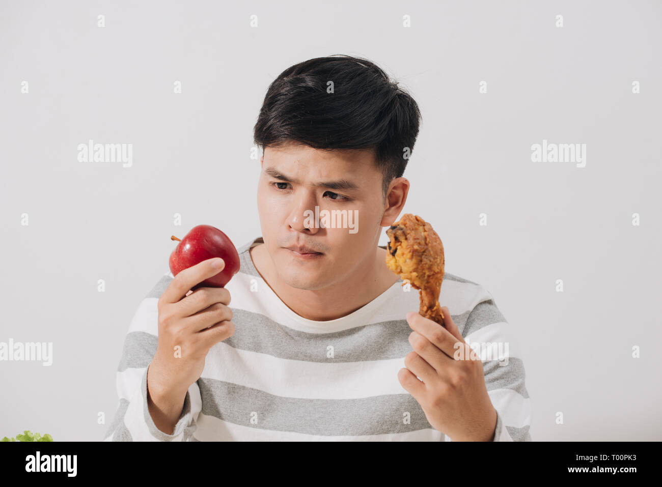 Man having hard choice between healthy and unhealthy food Stock Photo