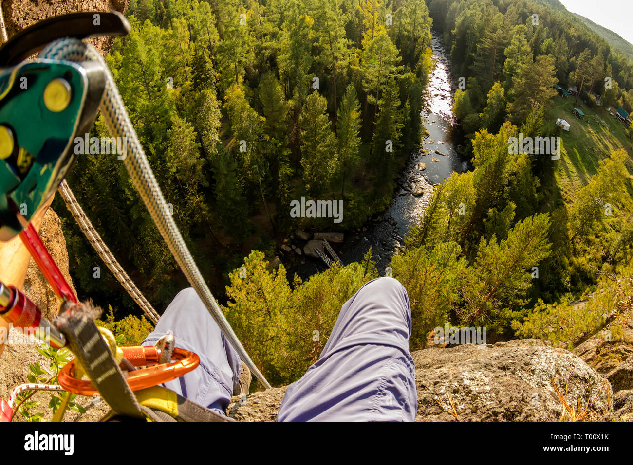 Climber's legs hanging on a rope in a harness, first person view to