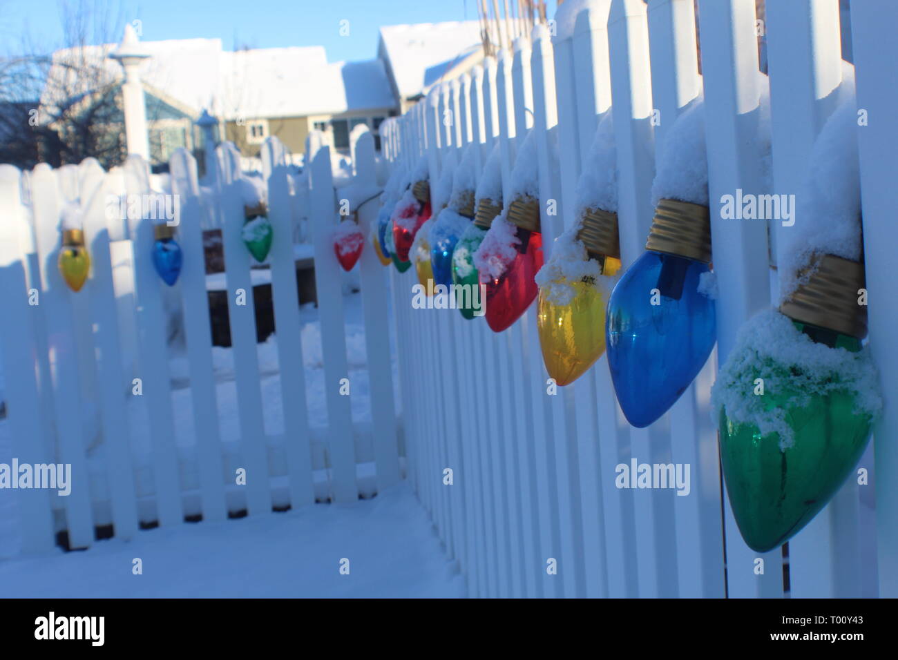 Christmas lights strung along white picket fence in the snow Stock Photo