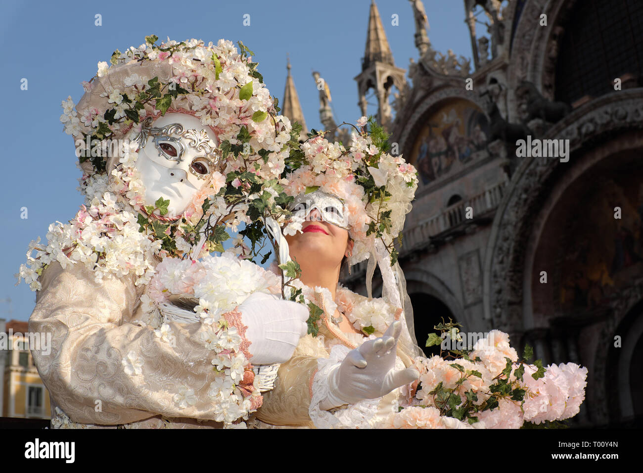 Couple dressed in traditional mask and costume for Venice Carnival standing in Piazza San Marco, Venice, Veneto, Italy Stock Photo