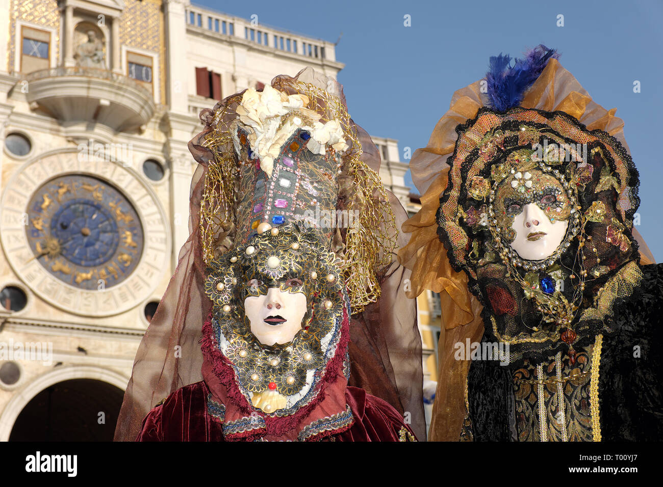 Couple dressed in traditional mask and costume for Venice Carnival standing in Piazza San Marco, Venice, Veneto, Italy Stock Photo