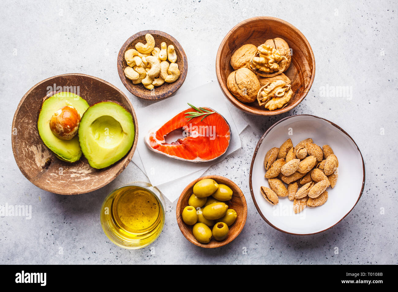 Selection of healthy fat sources fish, nuts, oil, olives, avocado on