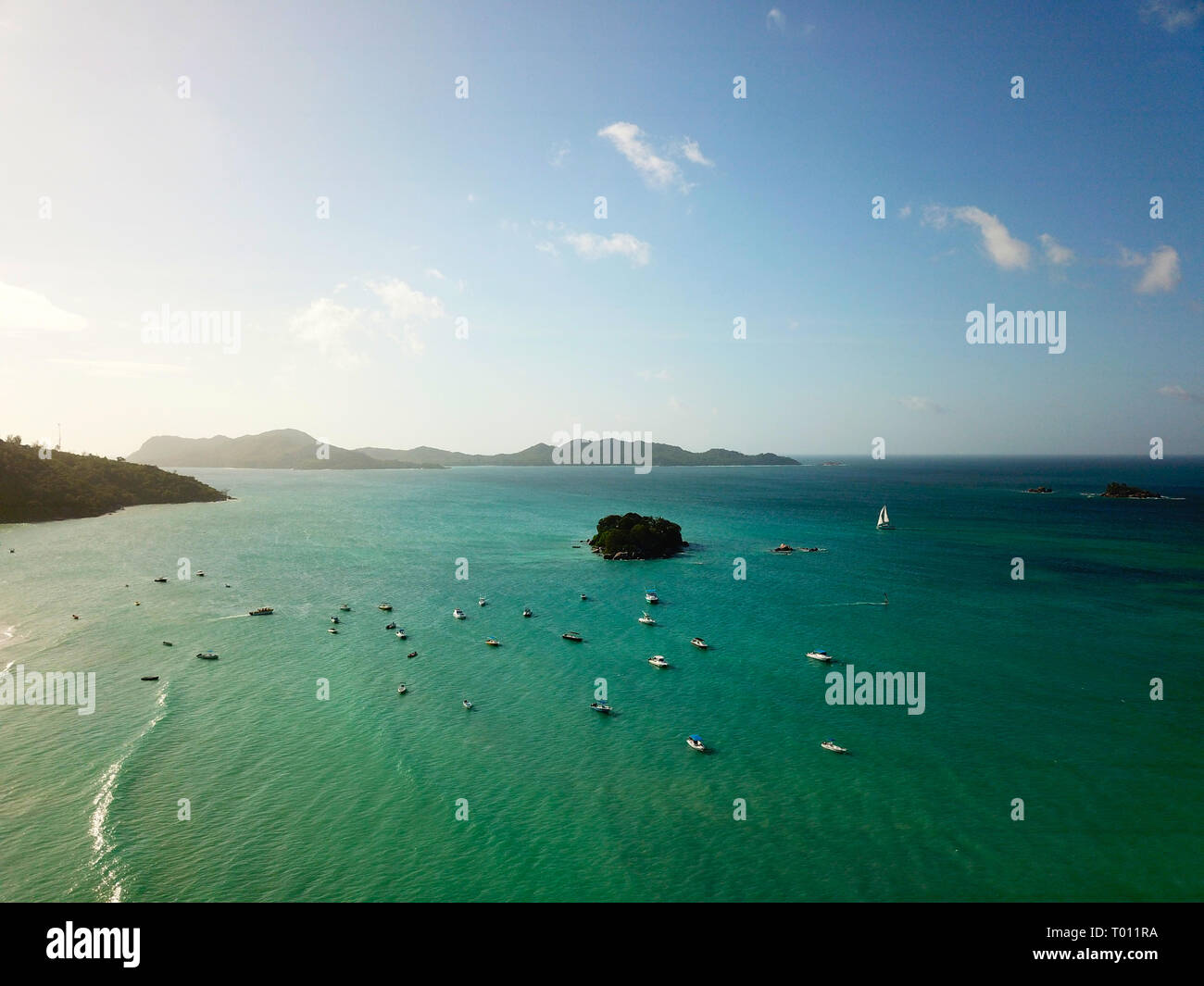 Many boats near the coast of Praslin. Curious Island, a sailing yacht and the horizon in the backround. Stock Photo