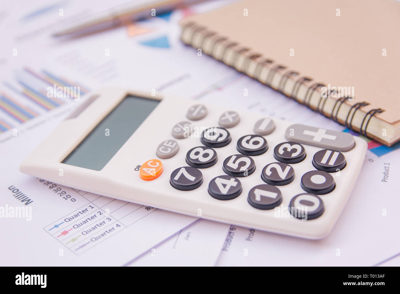 data analyzing with calculator, notebook and pen. on charts and graph ...
