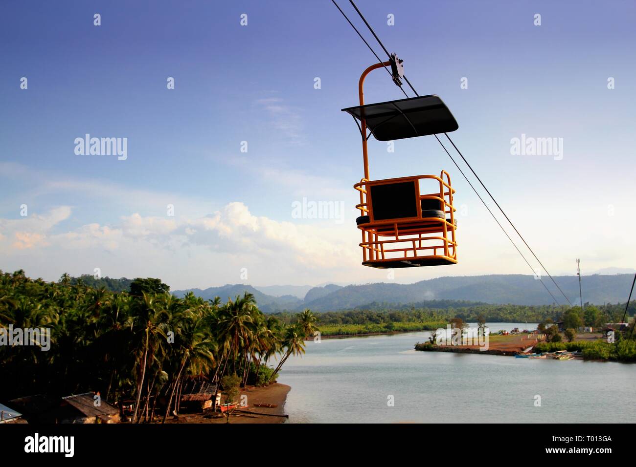 A cable car glides down thick cables above the river in Carrascal, Surigao del Sur, Philippines. Stock Photo