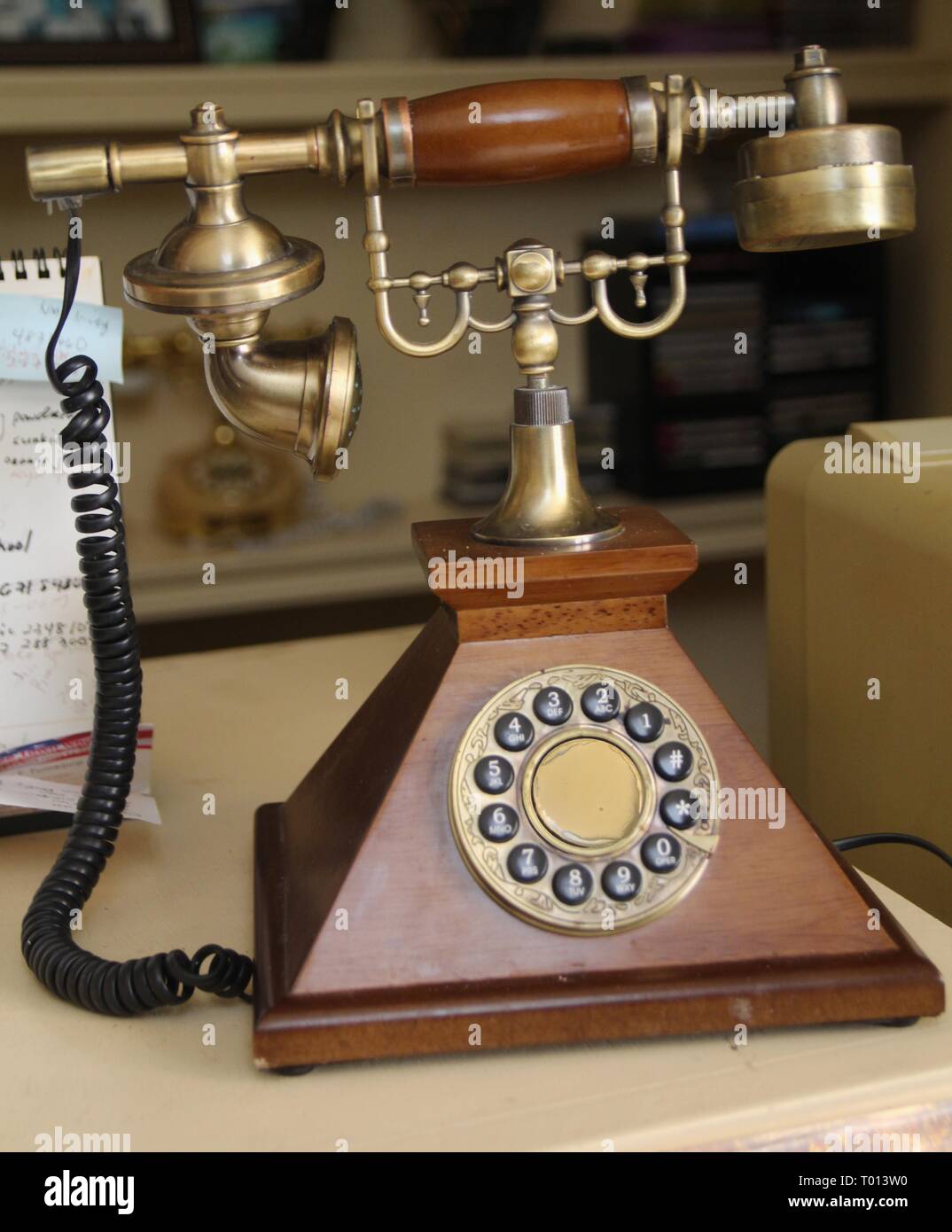 An Antique Telephone With Wooden Stand In A Cluttered Desk Stock