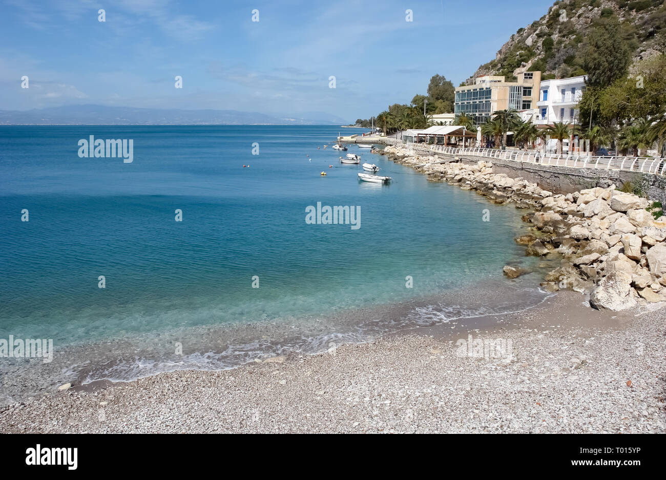Beautiful landscape with azure sea and a pebbly beach near the embankment of the Greek resort of Loutraki. Stock Photo
