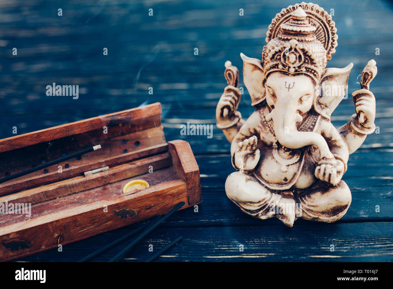 Hindu god Ganesh on black wooden background. Statue on table with  sandalwood stick close up with copy space for text Stock Photo - Alamy
