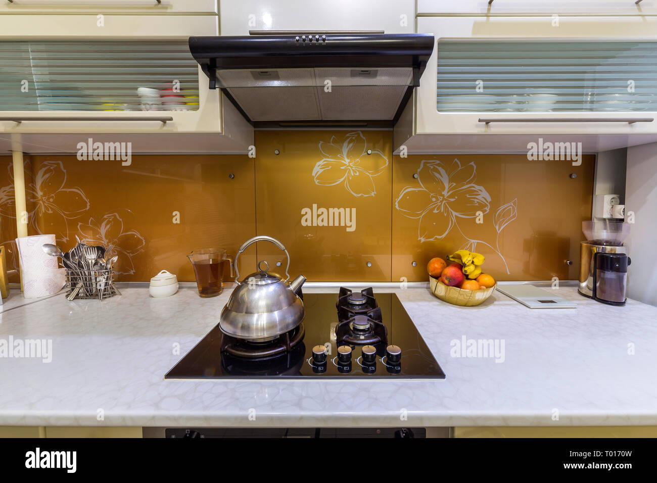 https://c8.alamy.com/comp/T0170W/shiny-stainless-tea-kettle-teapot-with-boiling-water-on-burning-gas-stove-on-modern-kitchen-yellow-interior-background-T0170W.jpg