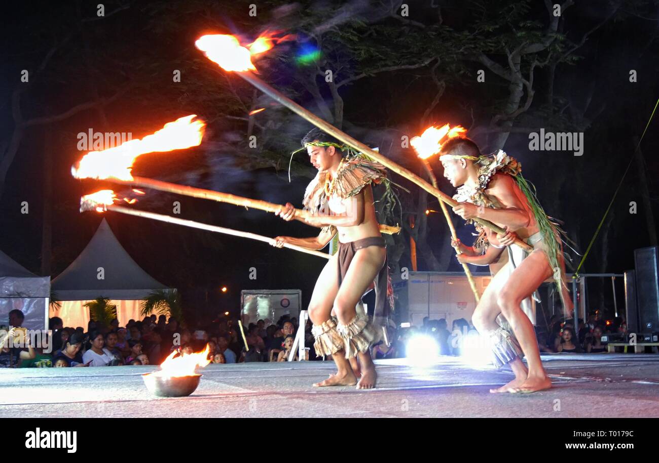 SAIPAN, NORTHERN MARIANA ISLANDS—Fire dancers entertain a crowd of spectators with live fire on poles at the Flame Tree Festival in April 2016. Stock Photo