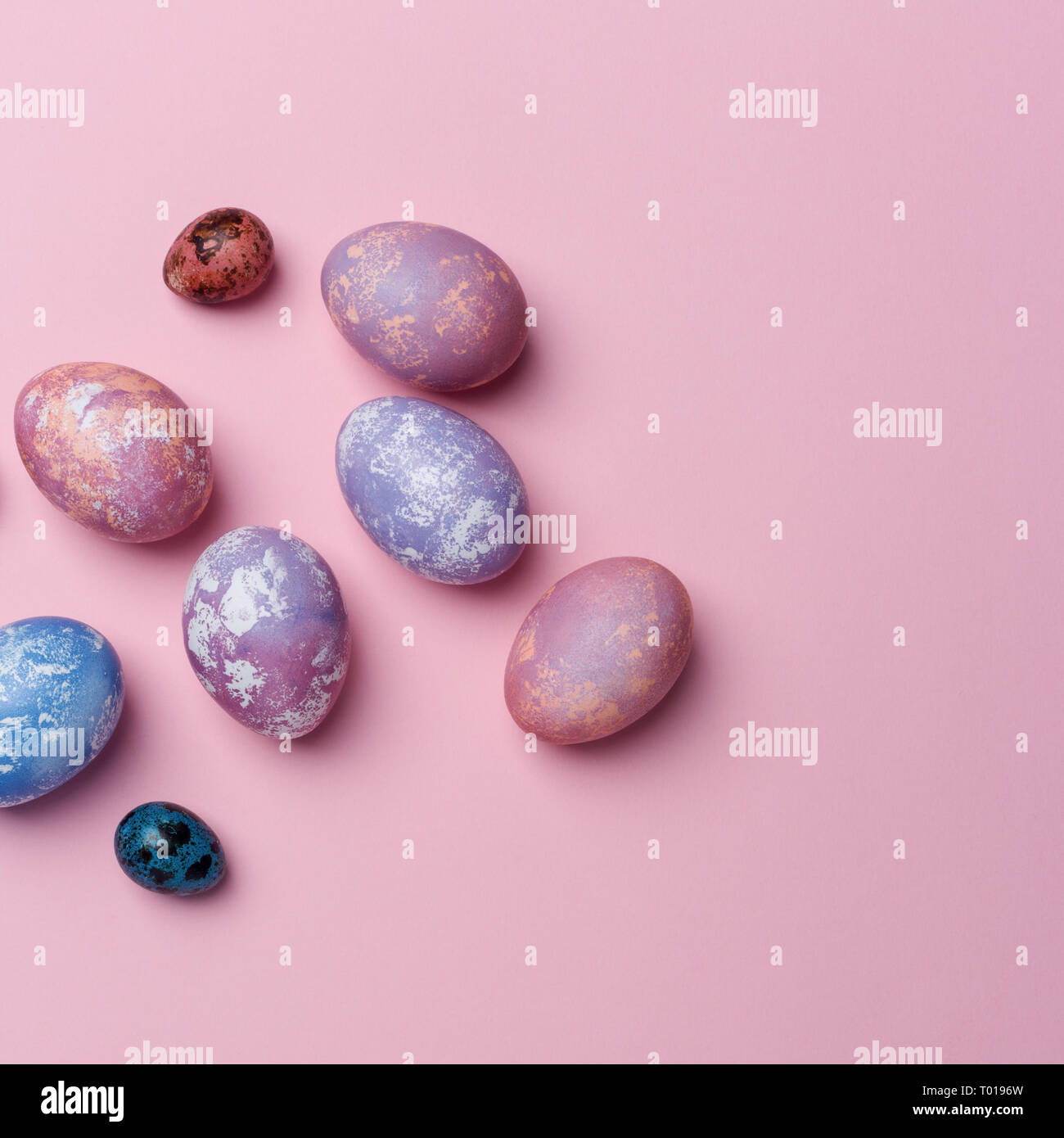 Multicolored eggs and quail eggs on pink background, copy space. Healthy food concept. Top view, flat lay. Easter eggs. Happy Easter concept Stock Photo