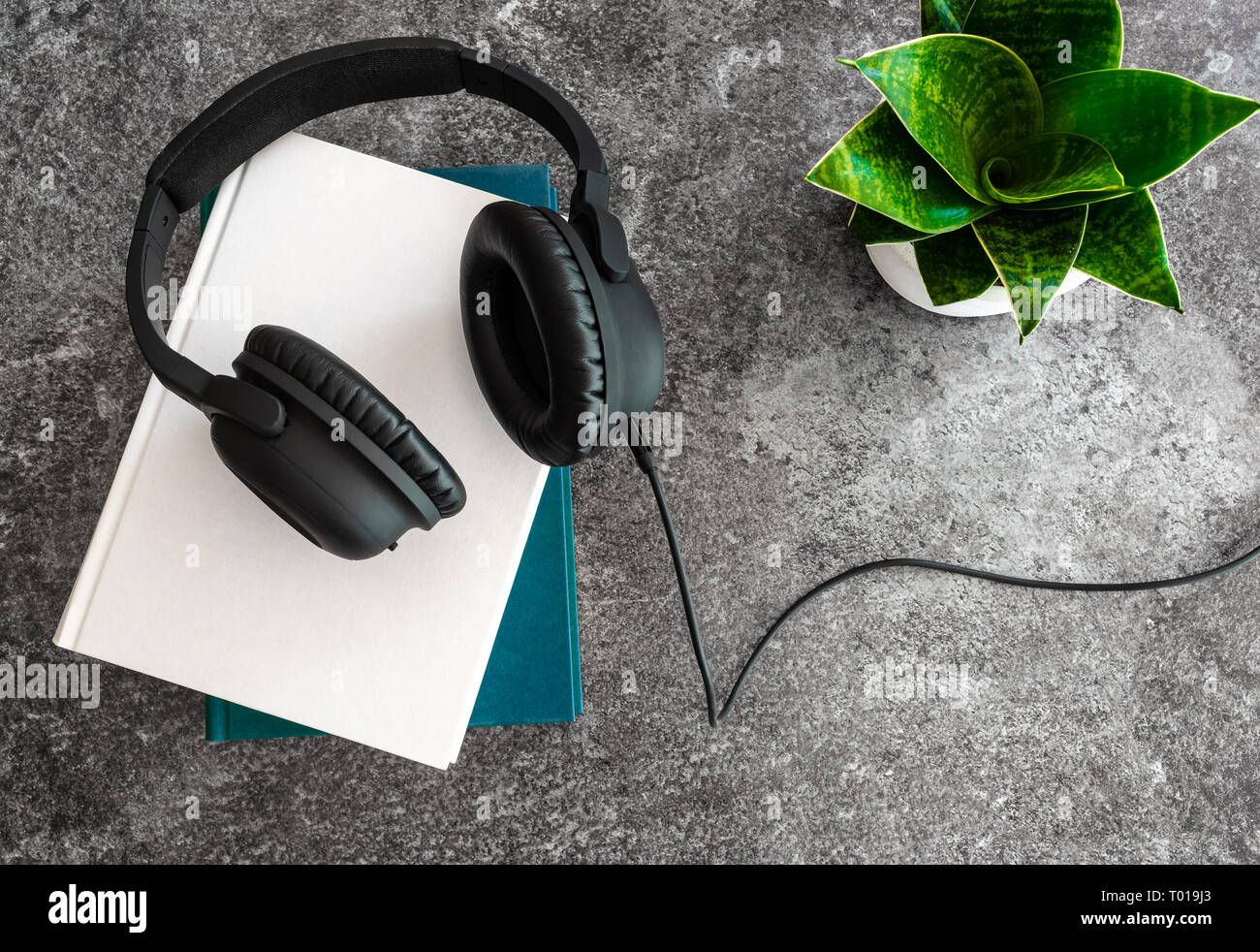listening to audio books concept with headphones on stack of books on stone background Stock Photo