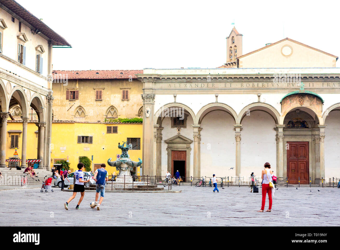 Teenaged boys kick a socerball around the Piazza della Santissima Annunziata, in Florence, in the region of Tuscany, Italy. Stock Photo