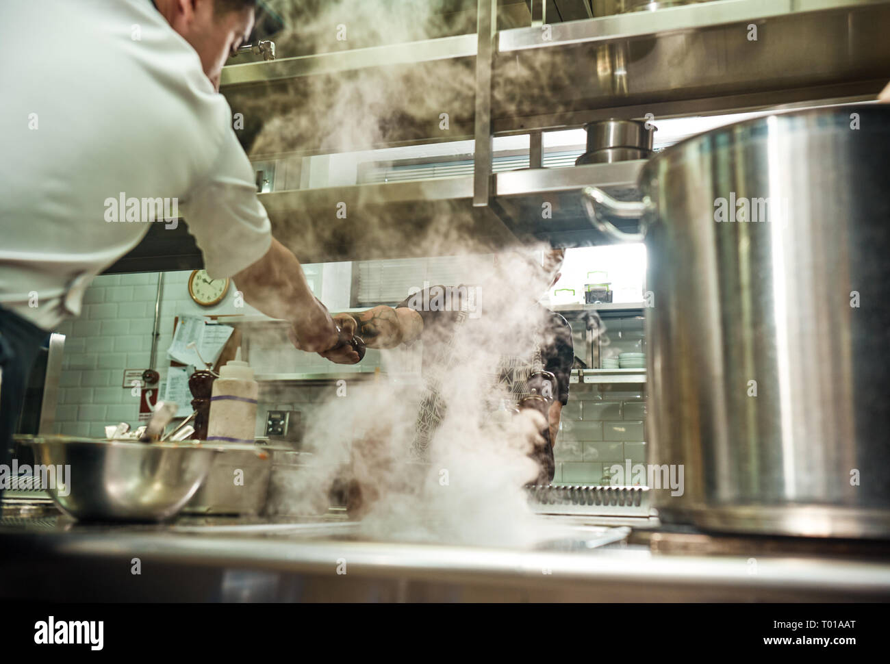 Teamwork. Restaurant chef giving a pepper grinder to his assistant