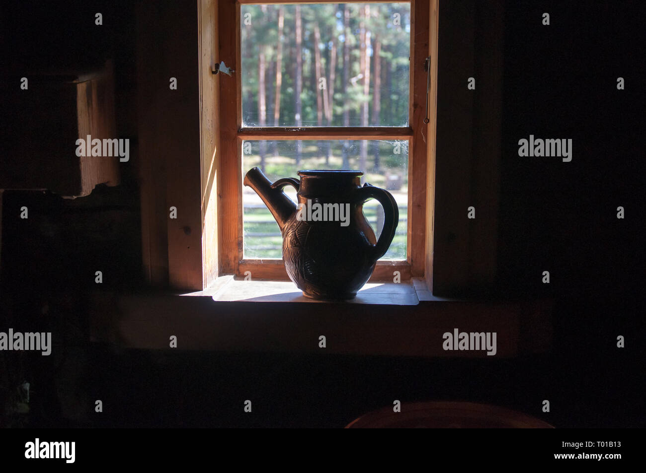 Clay jug stands on the window. Old wooden country house. Stock Photo