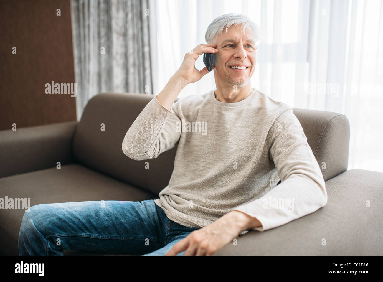 Adult man at home talking by mobile phone Stock Photo