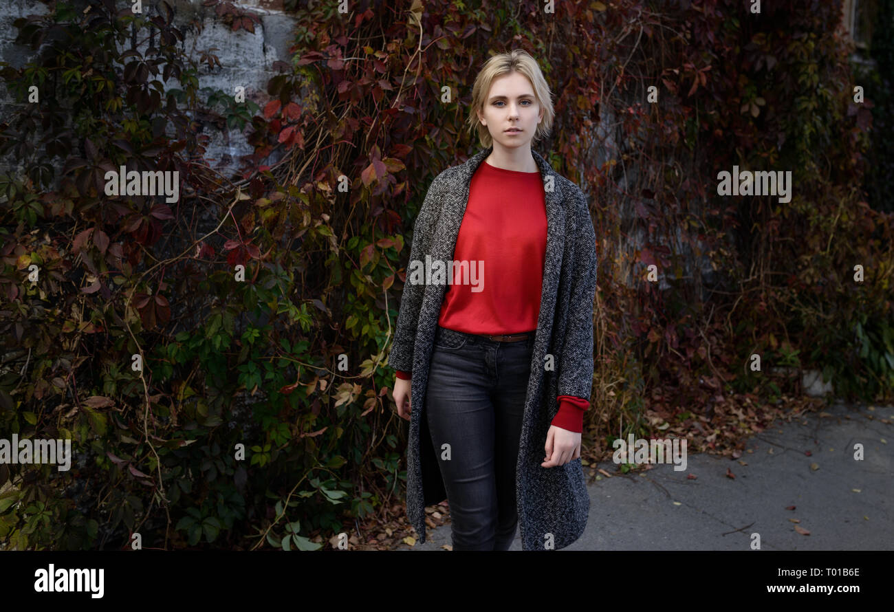 Young woman dressed in autumn coat and red sweater. Stock Photo