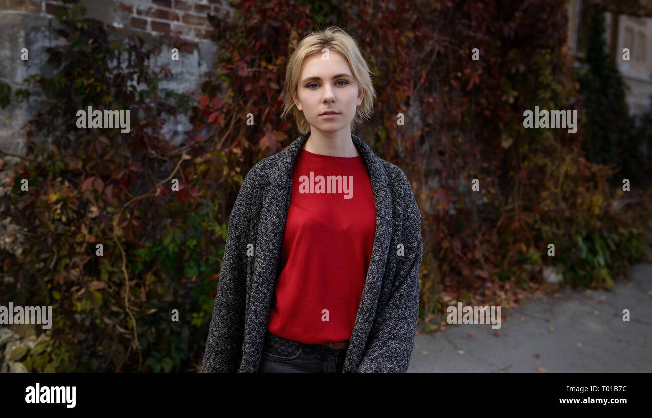 Young woman dressed in autumn coat and red sweater. Stock Photo