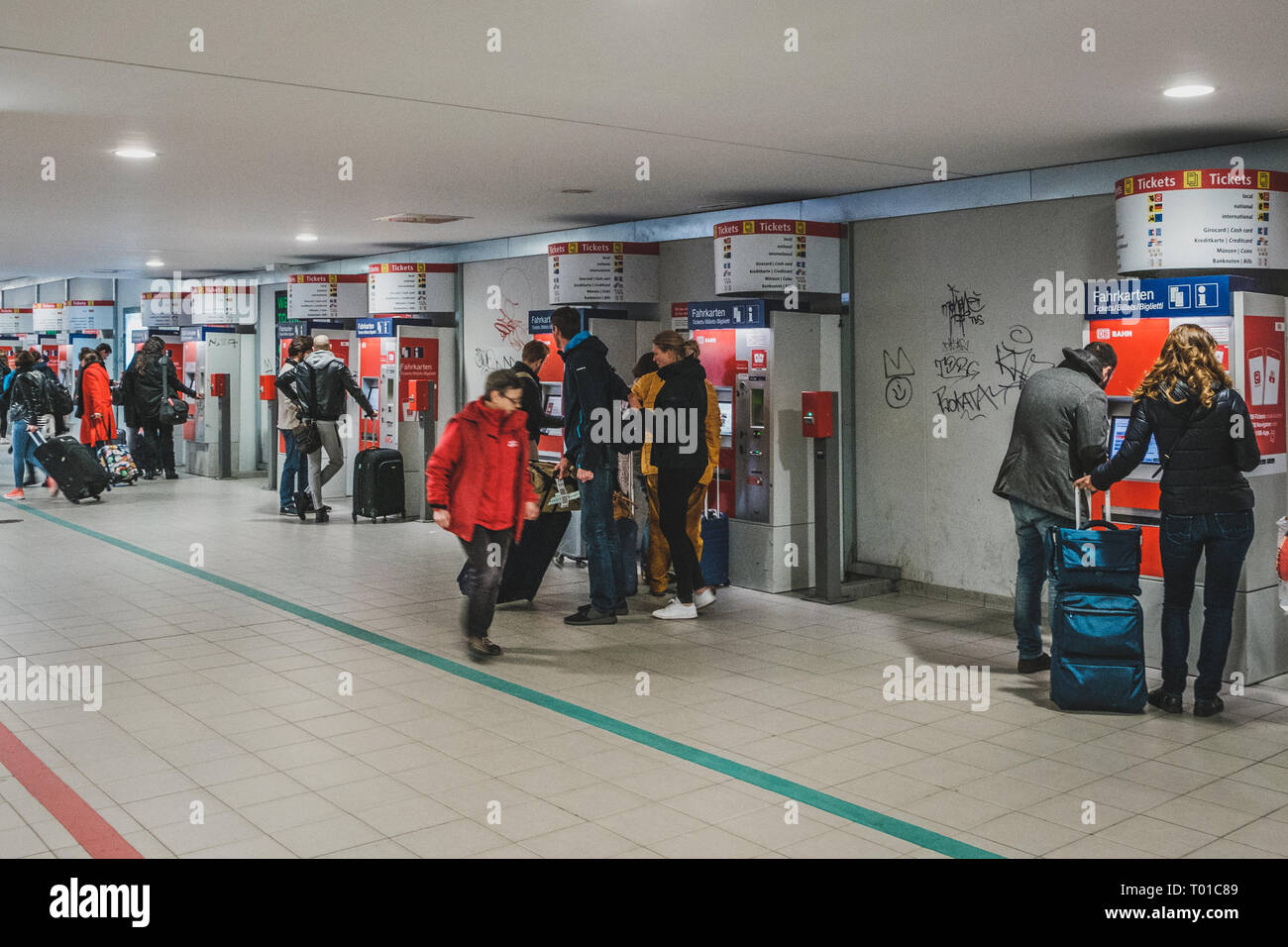 Berlin, Germany - march 2019: People with luggage buying train ticket at vending machine near airport in Berlin Stock Photo