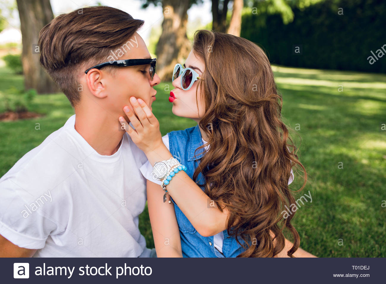 Portrait Of Cute Couple Of Young People On Grass In Park Pretty