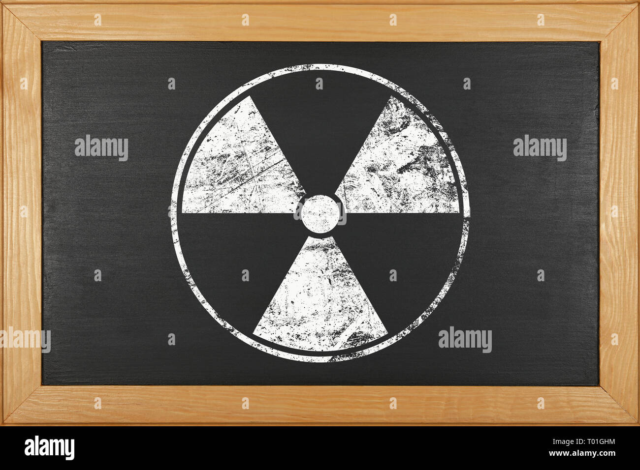 White chalk radioactive hazard warning sign over grunge black background of chalkboard with copy space Stock Photo