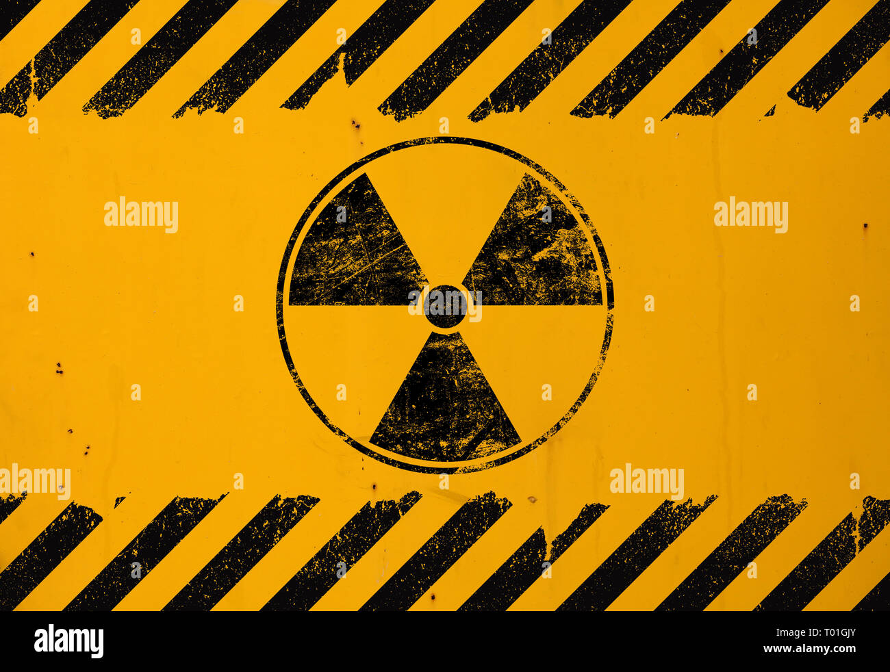 Black radioactive hazard warning sign painted over grunge yellow metal wall background with copy space Stock Photo