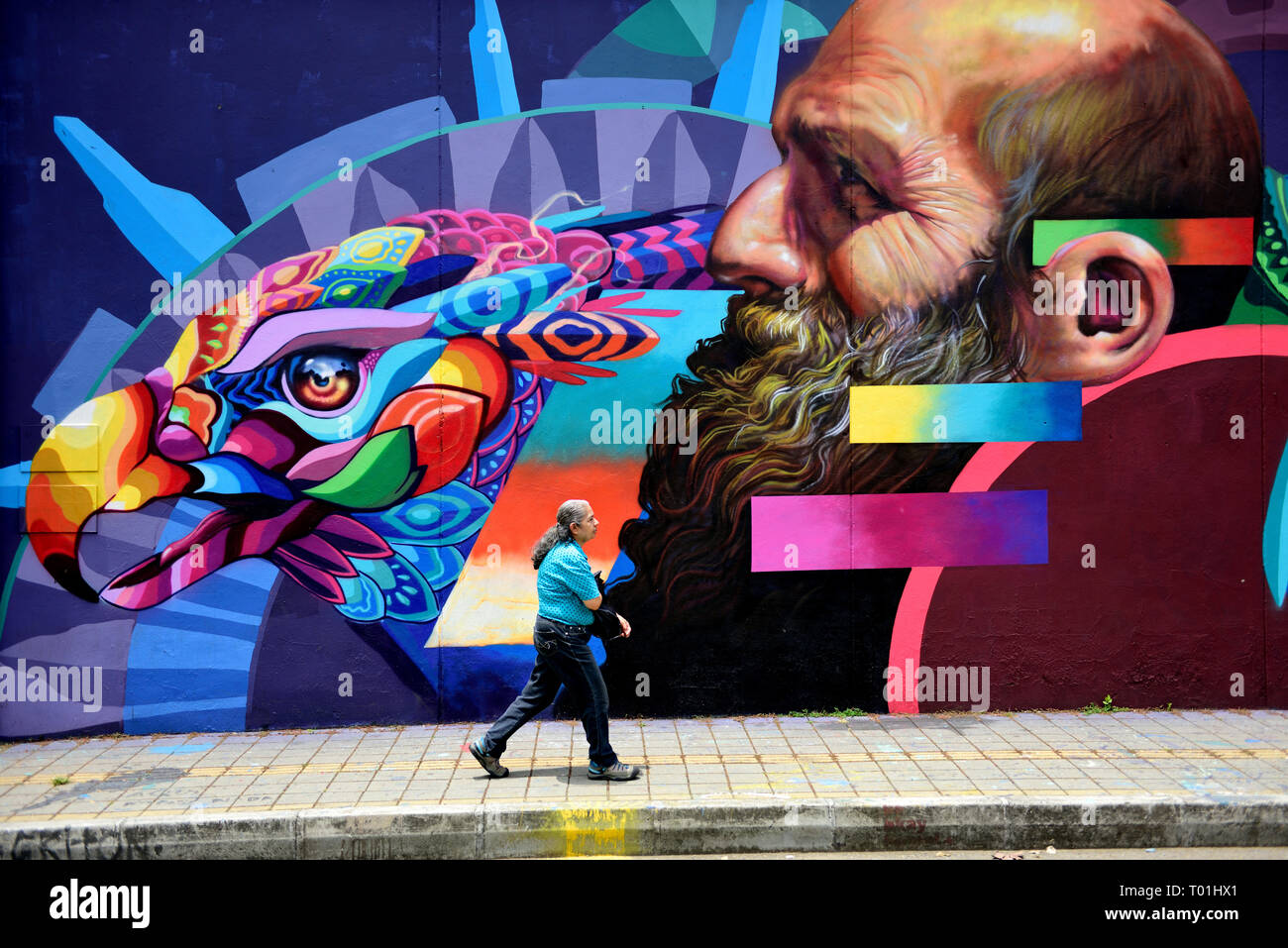 A woman walks by a large colorful Colombian street art in Medellin, Colombia, South America. Stock Photo