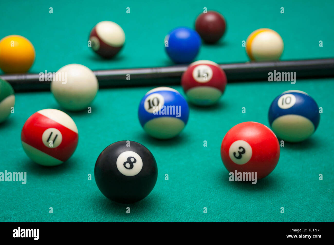 Lots of billiards and the cue on the billiard table, sports and recreation. Focused on the eight ball Stock Photo