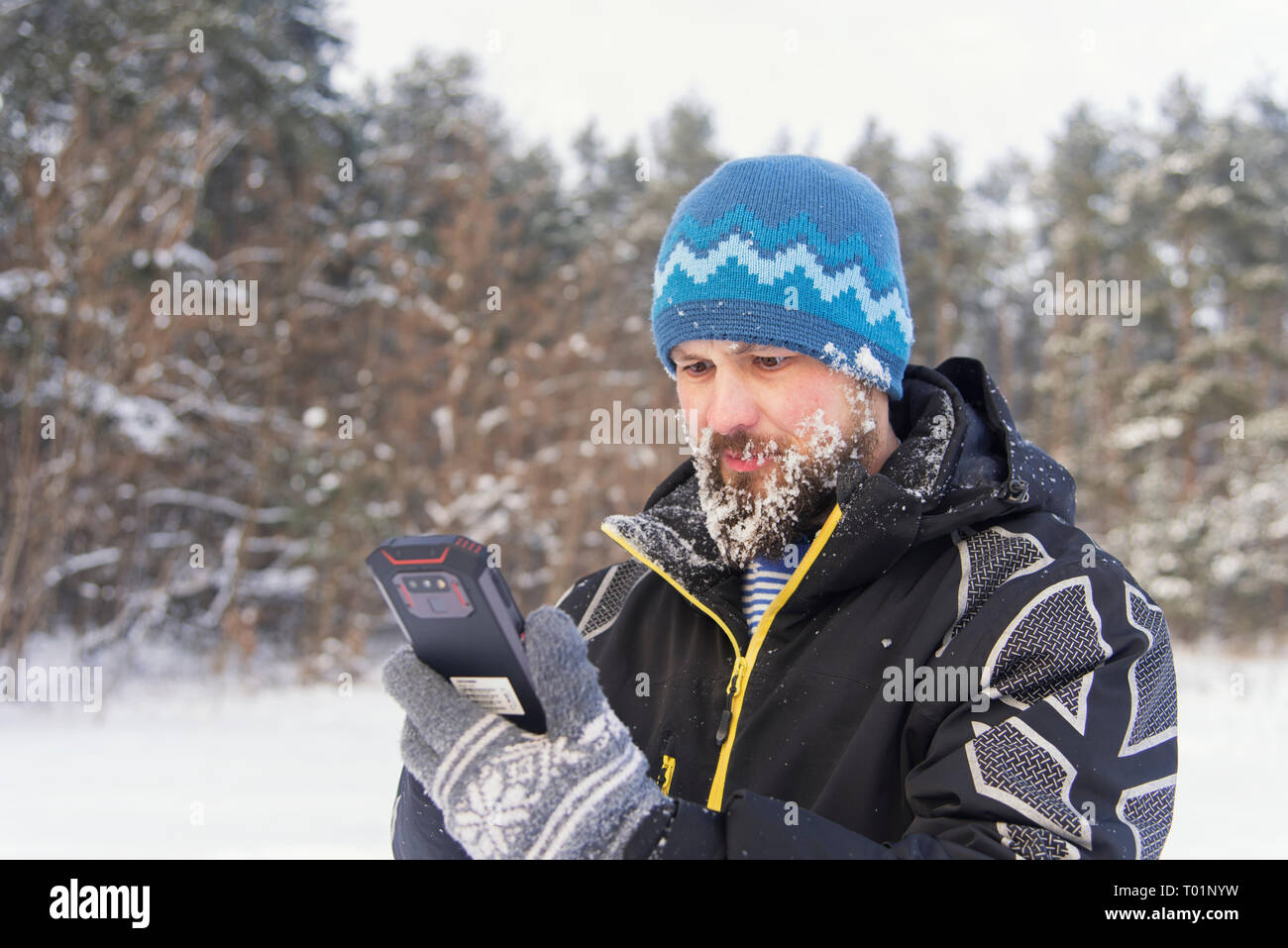 Bearded traveler with indignation looks at the phone, as there is no signal of cellular communication Stock Photo