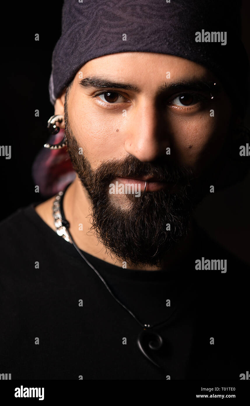 Dark close up portrait of a man with piercings and bandana. Stock Photo