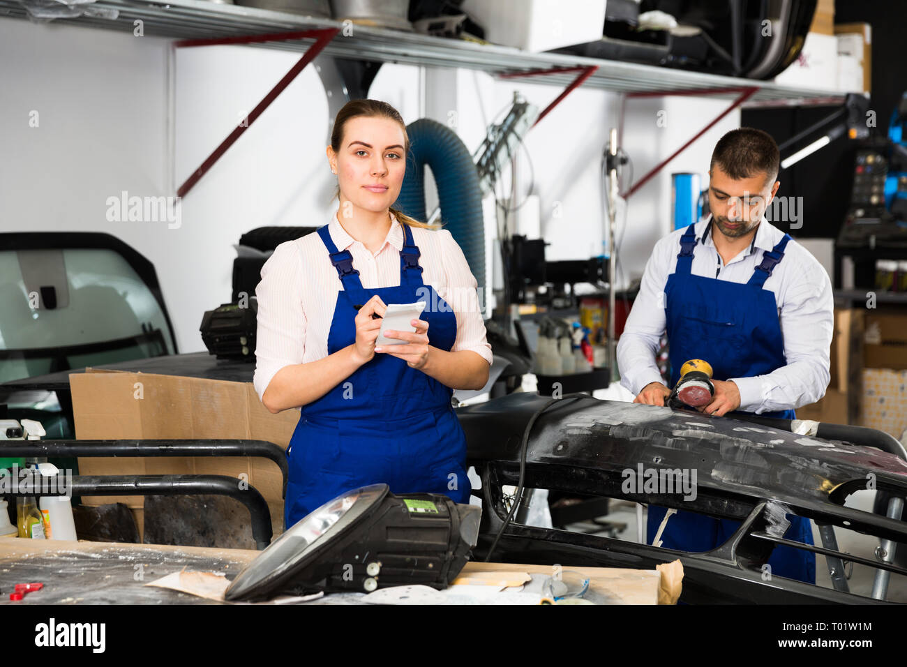 Professional female mechanic recording list of works on car repair in auto repair shop Stock Photo