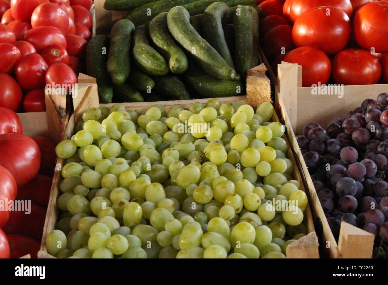 Grapes, tomatoes and cucumbers in crates at farmers whole food market Stock Photo