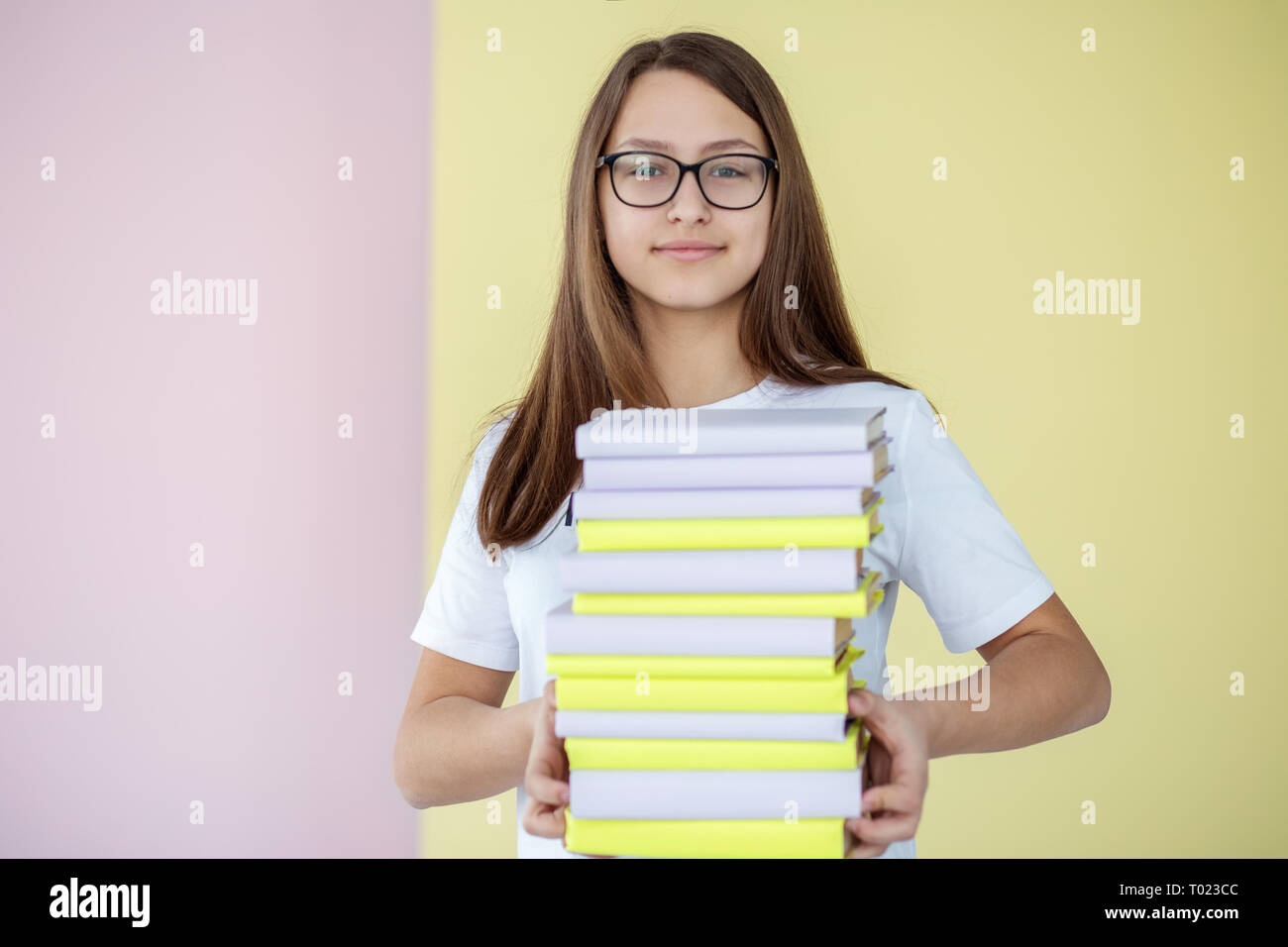 A smart teen girl holds many different textbooks. Back to school