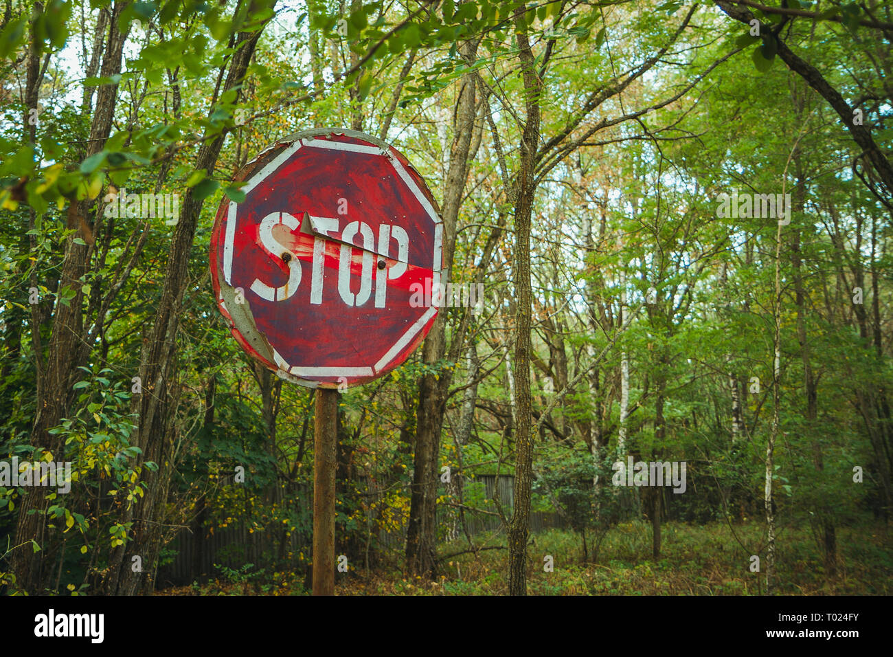 Stop sign - old rusty, frayed, scratched red road sign in radioactive zone in Pripyat city. Chornobyl exclusion zone Stock Photo