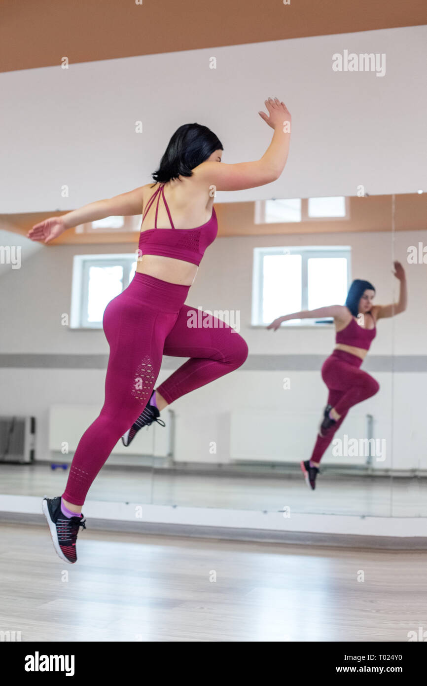 Athletic girl jumping in the gym. The concept of sports, a healthy lifestyle, losing weight Stock Photo