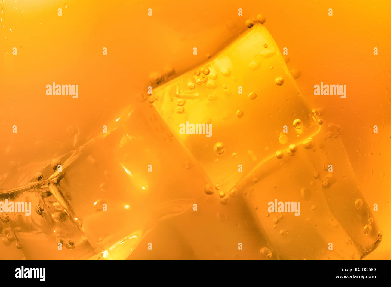 Blurred or defocused image of ice cubes in orange summer drinks Stock Photo